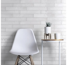 Wanddecoratie met witte, langwerpige tegels, gecombineerd met een stoel en een bijzettafel.