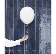 Hand houdt witte ballon vast voor blauwe wandtegel
