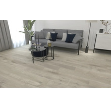 Lichte woonkamer met bank, tafel en houten vloer.