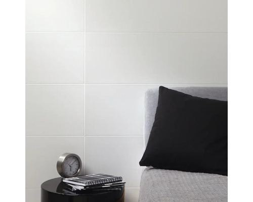 Wandtegels in slaapkamer met nachtkastje, kussen en klok